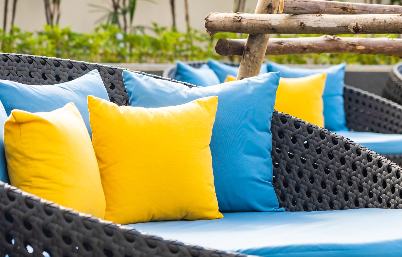 Yellow and blue pillows on wicker couch.