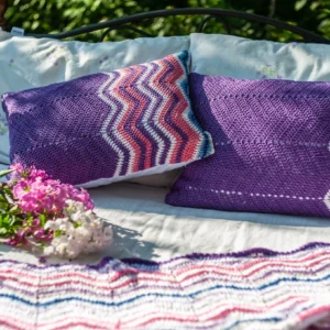 Purple crochet pillows on a bed outdoors.
