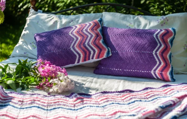 Purple crochet pillows on a bed outdoors.